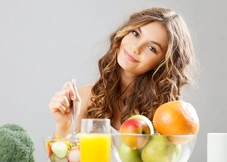 A woman sitting at the table with some fruit.