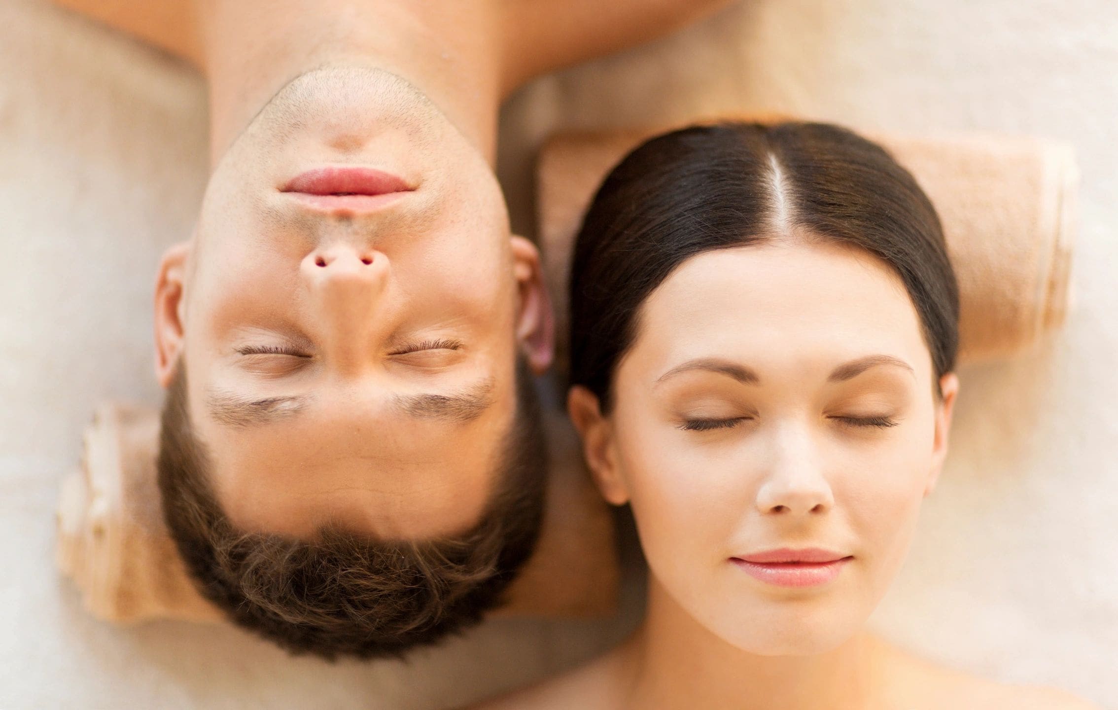 A man and woman laying on the ground with their eyes closed.