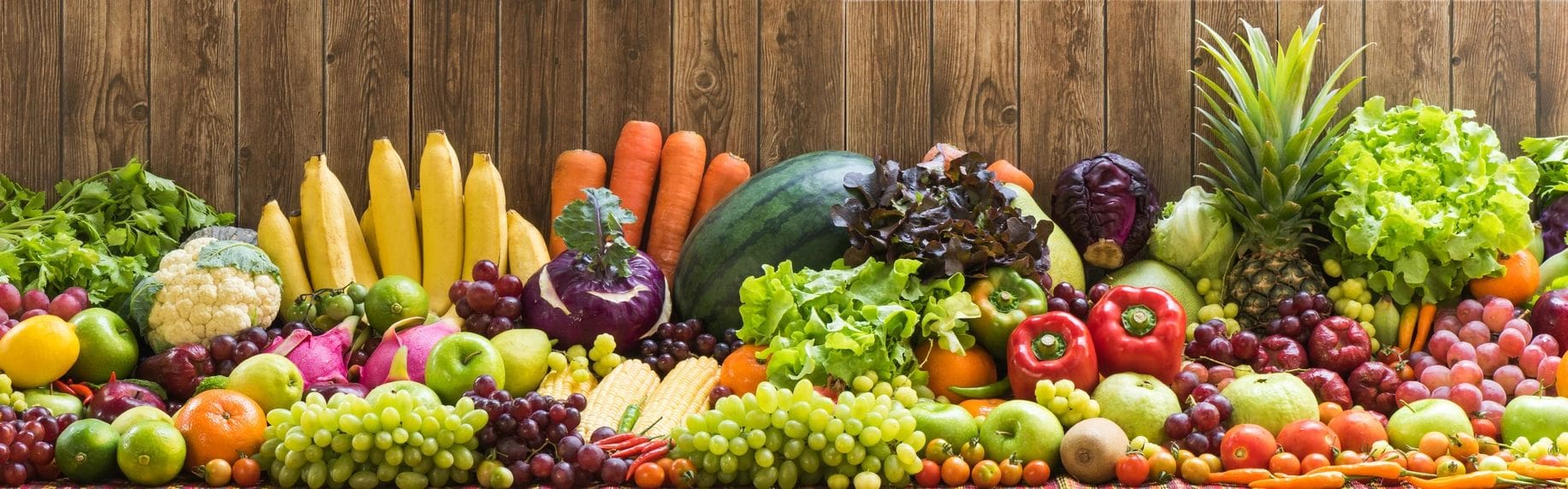 A wooden table topped with lots of fruits and vegetables.