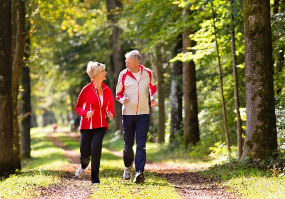 Two older women walking down a path in the woods.