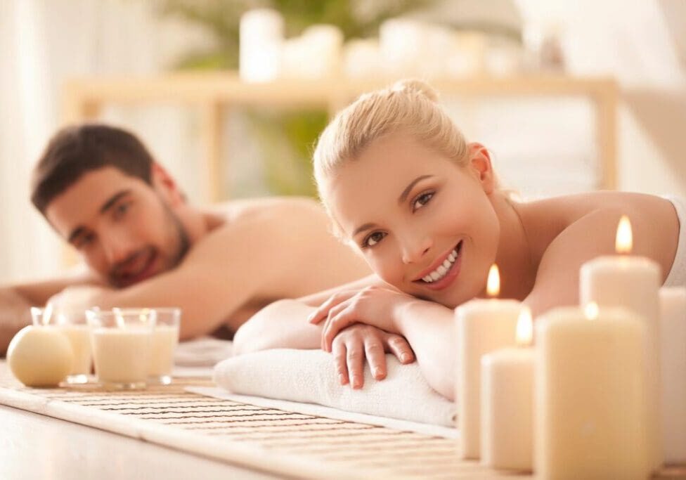 A man and woman laying on towels in front of candles.