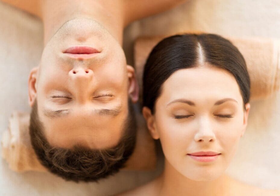 A man and woman laying on the ground with their eyes closed.